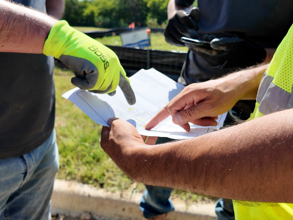 Geotechnical engineer and crew members reviewing a neighborhood lot map to plan post-injection soil sample locations during a site inspection.