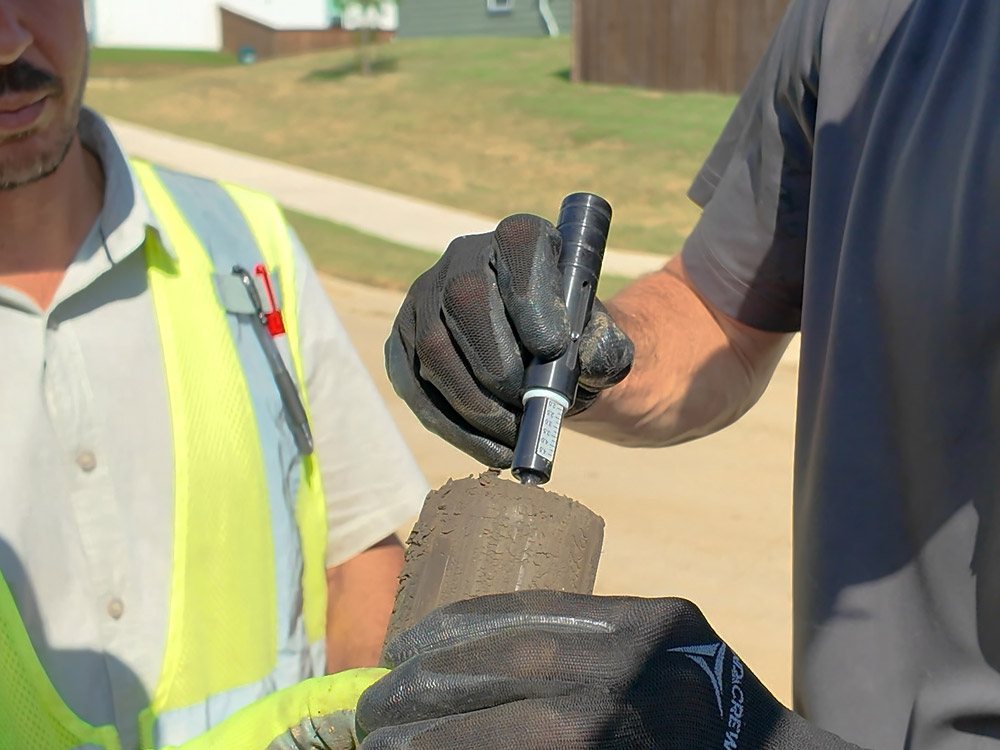 Technician uses penetrometer on clay soil core to assess PVR and soil collapse potential