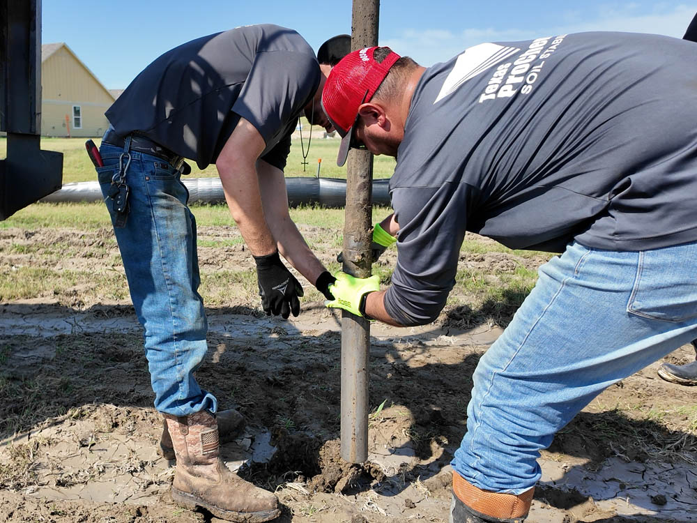 Field crew removes final section of 3-inch Shelby tube containing a soil sample during post-injection boring on a residential lot.